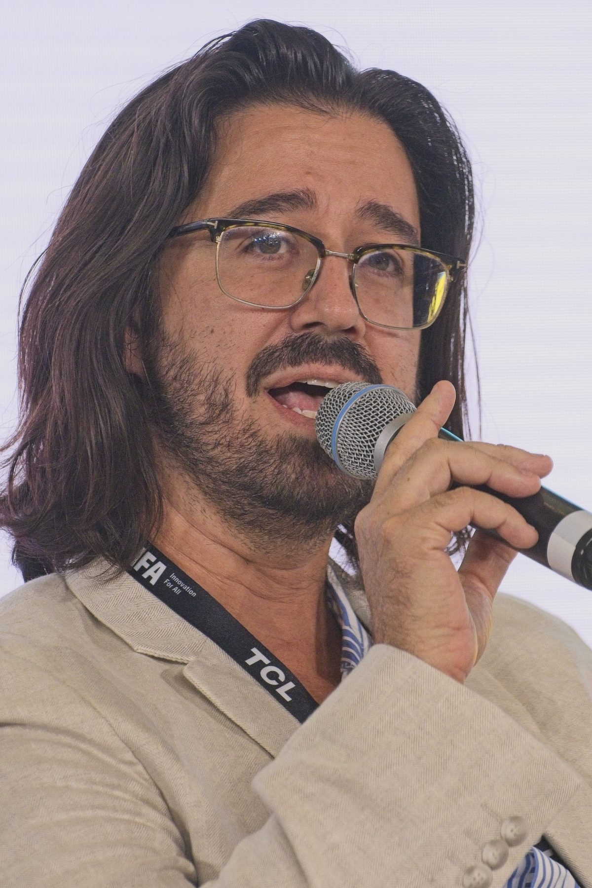 Jason Nellis speaking with a microphone on a panel at IFA Berlin